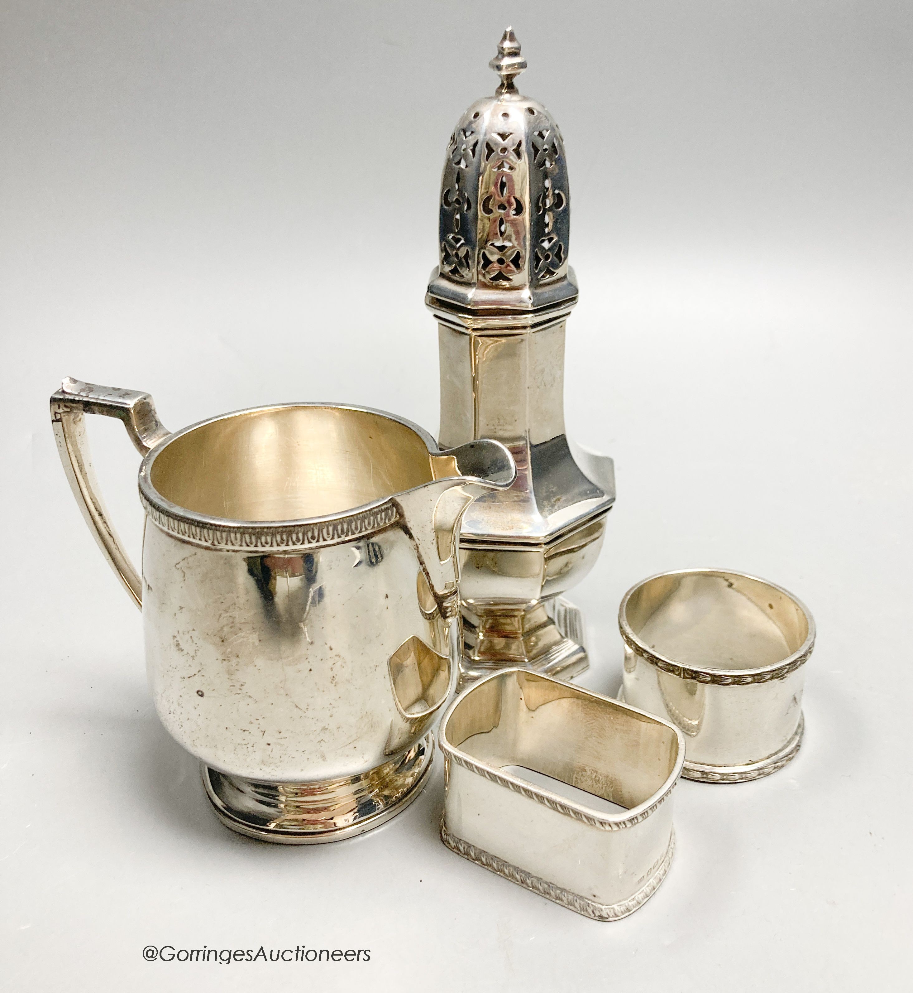A George V silver jug, Birmingham, 1928, a silver caster and two silver napkin rings, 10oz.